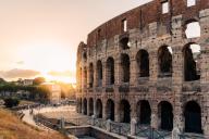 Outdoor view of The Colosseum or Coliseum with sun flare on background, also known as the Flavian Amphitheatre. It is an oval amphitheatre in the centre of Rome