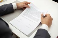 High angle view close up of male real estate agent holding a contract during meeting