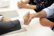 Close-up of real estate agent shaking hands with male client during meeting