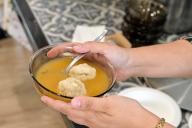 Jewish woman serving Matzah balls, Ashkenazi Jewish soup dumpling made from a mixture of matzah meal, eggs, water and chicken fat served on Passover Jewish Holiday