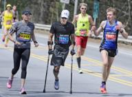 Wellesley, Massachusetts USA April 21, 2014 Larry Chloupek of Maryland, 53, uses forearm crutches to compete in the Boston Marathon. Running beside him is his wife and official guide, Jenn Chloupek. Runner Stefan Carisson of Sweden (at right) ...