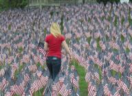 Boston, Massachusetts USA: May 22, 2014 A woman helps to plant some of thirty-seven thousand (37,000) American flags on Boston Common. It happened four days before Memorial Day. The number of flags marks how many soldiers died from Massachusetts ...
