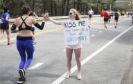 Wellesley, Massachusetts USA: April 17, 2017 A woman exhorts runners to kiss her during the Boston Marathon. Her sign includes a protest against the government. She is a student at Wellesley College, located along this stretch of the race. Some ...