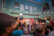 Audience member recording Bomba and Plena performance on smartphone at Tito Matos