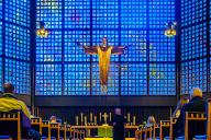 Congregants sit in peaceful reflection before the illuminated crucifix at Kaiser Wilhelm Memorial Church, Berlin