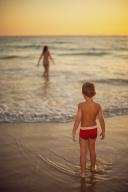 Two young children enjoy the sea at dusk on a sandy beach in the province of Cadiz, Spain