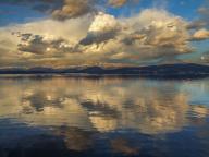 Cumulus clouds reflected in the calm waters of Lake Nahuel Huapi in Nahuel Huapi National Park in Argentina