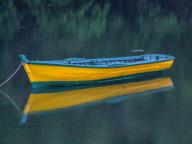 A colorful painted wooden boat moored and reflected in a small lake on Chiloe Island in Chile