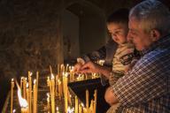 Man holding a boy lighting candles at Khor Virap Monastery; Ararat Province,