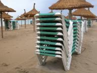Sonnenschirme und gestapelte Liegestuehle am Sandstrand, Spanien, Balearen, Mallorca | sunshades and stacked canvas chairs at sandy beach, Spain, Balearen,