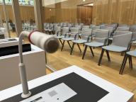 19 April 2024, Baden-Württemberg, Stuttgart: A microphone is attached to a table in the courtroom at the Higher Regional Court where the Reichsbürger trial is being heard. The defendants will sit behind glass partitions at seats with microphones. Photo: Nico Pointner\/dpa