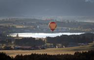 27 April 2024, Bavaria, Pfronten: A hot air balloon glides over Lake Hopfensee in the early morning. Photo: Karl-Josef Hildenbrand\/dpa