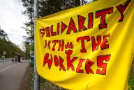 29 April 2024, Brandenburg, Grünheide (Mark): Activists from the "Stop Tesla" initiative have hung up a "Solidarity with the workers" banner at the edge of a protest camp in the forest near Fangschleuse, close to the Tesla Gigafactory Berlin-Brandenburg plant. By occupying the forest near the company\'s car factory, the activists are protesting against a planned plant expansion. The Brandenburg Health Minister Nonnemacher wants to find out about the working conditions at Tesla Grünheide in the morning. Photo: Soeren Stache\/dpa