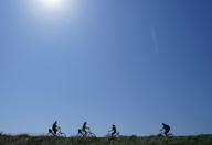 02 May 2024, Schleswig-Holstein, St. Peter-Ording: Passers-by ride their bicycles on the dyke. Photo: Marcus Brandt\/dpa
