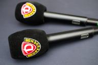 04 May 2024, Saxony, Dresden: Soccer: 3rd division, SG Dynamo Dresden - SC Verl, matchday 36, Rudolf-Harbig-Stadion. Microphones with the Dynamo Dresden logo lie on a table. Photo: Robert Michael\/dpa