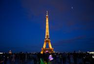06 May 2024, France, Paris: Tourists stand in front of the Eiffel Tower in the evening. The Olympic Games and Paralympics take place in France in the summer. Photo: Robert Michael\/dpa