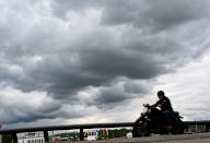 07 May 2024, Rhineland-Palatinate, Ingelheim am Rhein: A motorcyclist is on the road at the Ingelheim ferry landing stage while dark rain clouds gather in the sky over the Rhine (shot with slower shutter speed). Photo: Arne Dedert\/dpa
