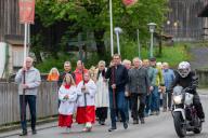 09 May 2024, Bavaria, Roßhaupten: A motorcyclist passes parishioners on their way to church. Outside the churches, the day of Ascension was nicknamed "Father\'s Day". It is celebrated with gentlemen\'s parties and drinking bouts. Photo: Stefan Puchner\/dpa