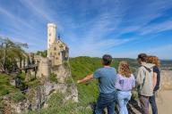 12 May 2024, Baden-Württemberg, Lichtenstein: Excursionists stand on a viewing platform and look out over Lichtenstein Castle in the Swabian Alb. Photo: Thomas Warnack/dpa