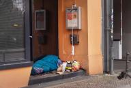 18 December 2023, Berlin: 18.12.2023, Berlin. On a day in December, a homeless man lies with his belongings in a building entrance next to a sidewalk and sleeps in a sleeping bag. He taps electricity from a socket outside for his cell phone and another device. Photo: Wolfram Steinberg/dpa Photo: Wolfram Steinberg/dpa
