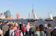 12 May 2024, Hamburg: Numerous spectators at the Landungsbrücken watch the departure parade of the traditional sailing ships during the 835th Hamburg Harbour Birthday on the Elbe in the harbour. The Elbphilharmonie concert hall can be seen in the background. The people of Hamburg regard May 7, 1189 as the birthday of their port - back then, citizens were granted duty-free travel for their ships on the Elbe from the city to the North Sea. Photo: Georg Wendt/dpa
