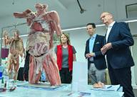 13 May 2024, Brandenburg, Guben: Dietmar Woidke (r, SPD), Minister President of Brandenburg, Rurik von Hagens, Managing Director of Gubener Plastinate GmbH and Ines Drenkow, employee, stand in the workshop where human bodies are mainly produced for teaching purposes, but also for exhibitions such as the "Body Worlds" by the cadaver dissector von Hagens. Rurik von Hagens is the son of the well-known physician, anatomist and entrepreneur, Gunther von Hagens. The Minister President visited the Plastinarium and learned about the company during a tour of the premises. Photo: Patrick Pleul/dpa