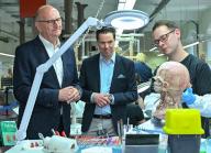 13 May 2024, Brandenburg, Guben: Dietmar Woidke (l, SPD), Minister President of Brandenburg, Rurik von Hagens (M), Managing Director of Gubener Plastinate GmbH and Florian Zschiesche, employee, stand in the workshop where human bodies are mainly produced for teaching purposes, but also for exhibitions such as the "Body Worlds" by the cadaver dissector von Hagens. Rurik von Hagens is the son of the well-known physician, anatomist and entrepreneur, Gunther von Hagens. The Minister President visited the Plastinarium and learned about the company during a tour of the premises. Photo: Patrick Pleul/dpa
