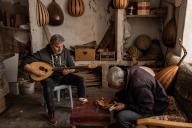 12 May 2024, Syria, Al Bab: A man plays the oud instrument while Hassan Hamza (R), 68, working at his workshop. Musician Hamza crafts the Middle Eastern stringed instrument in a month, being the only Oud maker in Al-Bab. Photo: Anas Alkharboutli/dpa