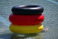 15 May 2024, Thuringia, Weimar: Three rubber tires in black, red and yellow lie in the water of Weimar