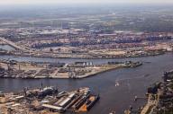 14 May 2024, Hamburg: View across the Elbe into the port of Hamburg with the Blohm + Voss shipyard (foreground), VERA sewage sludge incineration plant of Hamburg Wasser on the Köhlbrand dyke (M) and container terminals (aerial view). Photo: Christian Charisius\/dpa