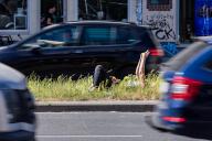 16 May 2024, Berlin: A woman lies in the sun on the central reservation of Frankfurter Allee in Berlin-Friedrichshain. Photo: Christoph Soeder/dpa