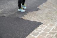 16 May 2024, Bavaria, Schweinfurt: A person stands on the new road surface. The asphalt of the road is to be torn up and renewed because of the wrong color. Photo: Daniel Vogl\/dpa