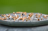 PRODUCTION - 15 May 2024, Hesse, Offenbach/Main: Cigarette butts are stuck on a garbage can with an ashtray at a sports facility. Cigarette butts are considered toxic hazardous waste. Many smokers carelessly throw their butts on the ground. Photo: Arne Dedert/dpa