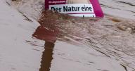 18 May 2024, Rhineland-Palatinate, Trier: An election poster for the European elections stands in the water on the Zurlauben riverbank. The German Weather Service has issued the highest warning level for Trier. Photo: Andreas Arnold/dpa