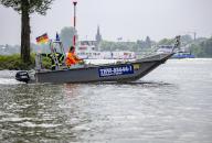 18 May 2024, North Rhine-Westphalia, Niederkassel: Emergency boats from the Federal Agency for Technical Relief (THW) sail along the banks of the Rhine. Several funfair rides and a Ferris wheel at a beach festival had to close on Saturday due to the rising Rhine level. Photo: Thomas Banneyer/dpa