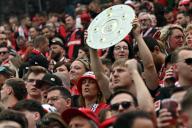 18 May 2024, North Rhine-Westphalia, Leverkusen: Soccer: Bundesliga, Bayer Leverkusen - FC Augsburg, Matchday 34, BayArena. Leverkusen fans hold up a replica of the championship trophy. Photo: Federico Gambarini/dpa - IMPORTANT NOTE: In accordance with the regulations of the DFL German Football League and the DFB German Football Association, it is prohibited to utilize or have utilized photographs taken in the stadium and/or of the match in the form of sequential images and/or video-like photo series