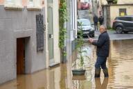 20 May 2024, Rhineland-Palatinate, Zell: A man photographs a small tree in a street in the flooded old town after the Moselle rose over the edge of the flood protection wall overnight. Photo: Thomas Frey/dpa