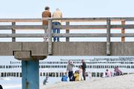 19 May 2024, Mecklenburg-Western Pomerania, Graal-Müritz: Walkers stand on the pier on the busy Baltic Sea beach in Graal-Müritz. The Whitsun weather on the German Baltic coast is mixed. Photo: Frank Hormann/dpa