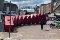 17 May 2024, Great Britain, Kingston-Upon-Thames: Pedestrians walk past an installation with red telephone boxes. Photo: Benedikt von Imhoff/dpa