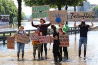 20 May 2024, Saarland, Saarbrücken: Climate activists from the group "Fridays for Futures" hold signs reading "Climate crisis", "Climate protection = human protection" on the flooded Autobahn 620 at the old bridge in Saarbrücken. The activists accuse Chancellor Scholz of having "negligently ignored the climate crisis" during his visit and in his speech. Photo: Christian Wiediger/dpa
