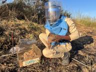 03 May 2024, Angola, Calulo: "Rat leader" Raul Ilidio takes the rat Baraka out of her cage to put her on a minefield. A small harness is put on her. The rodent is one of twelve giant hamster rats that sniff out landmines underground in Angola