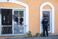 21 May 2024, Brandenburg, Hoppegarten: A police officer secures evidence on the door of a restaurant in Hoppegarten. A window in the restaurant had been smashed, the façade smeared and butyric acid distributed. The restaurant had recently been the venue for a right-wing book fair hosted by an AfD politician. The fire department was deployed with around 20 vehicles because of the butyric acid. Photo: Christophe Gateau/dpa