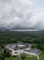 22 May 2024, Hesse, Eltville: Dark rain clouds pass over Eberbach Monastery in the Rheingau (aerial photo taken with a drone). The weather continues to be changeable. Photo: Boris Roessler/dpa