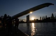 22 May 2024, Hesse, Frankfurt/Main: Rowers lift their boat out of the Main in the last light of the day. The weather is expected to be changeable in the coming days. Photo: Boris Roessler/dpa
