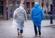 23 May 2024, Mecklenburg-Western Pomerania, Wismar: Walkers with rain jackets are out and about in the city harbor. With rain and cool temperatures of around 15 degrees, the weather in northern Germany is showing its changeable side. Photo: Jens Büttner/dpa