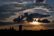 23 May 2024, Hesse, Frankfurt/Main: The sun sets over the ECB and the silhouettes of Frankfurt am Main