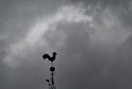 24 May 2024, Baden-Württemberg, Stuttgart: Dark rain clouds hover above a weathercock. Photo: Bernd Weißbrod/dpa