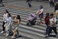 24 May 2024, Mexico, Mexiko-Stadt: A woman crosses the street with her baby carriage, the child has been covered with a cloth due to the sun