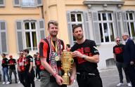26 May 2024, Leverkusen: Bayer Leverkusen goalkeeper Lukas Hradecky (left) and coach Xabi Alonso pose with the German Cup trophy in front of Morsbroich Palace, where they signed the city