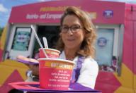 27 May 2024, Hamburg: Carola Veit (SPD), President of the Hamburg Parliament, holds up two ice cream sundaes in front of a pink ice cream van as part of the election motivation campaign "Vote for what moves you!" in the parking lot of a DIY store in the Harburg district. With flyers and a free scoop of ice cream, Veit promoted the participation of Hamburg